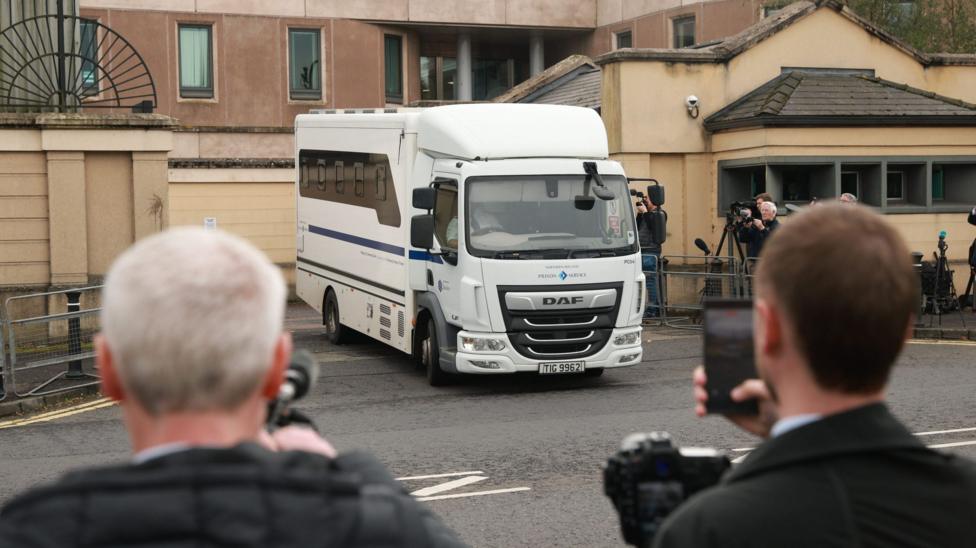 A white prison van carrying Jeffrey Donaldson travels past camera crews outside Newry courthouse.