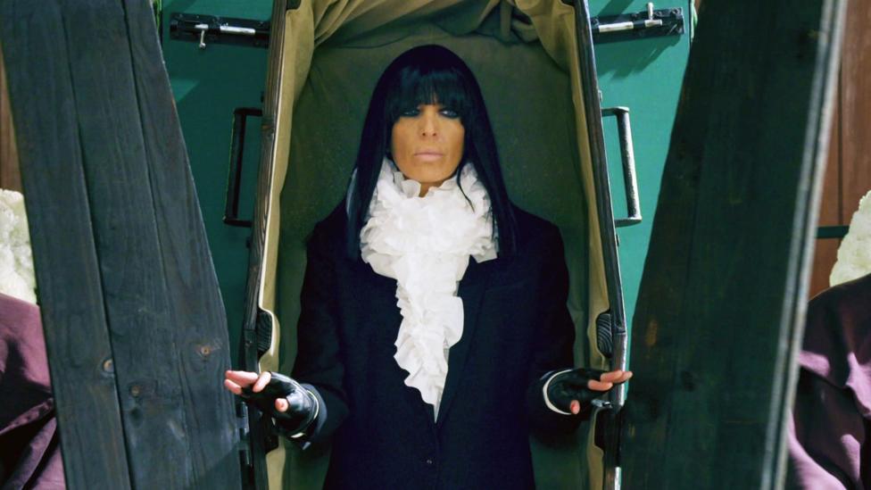 Claudia Winkleman emerging from a coffin