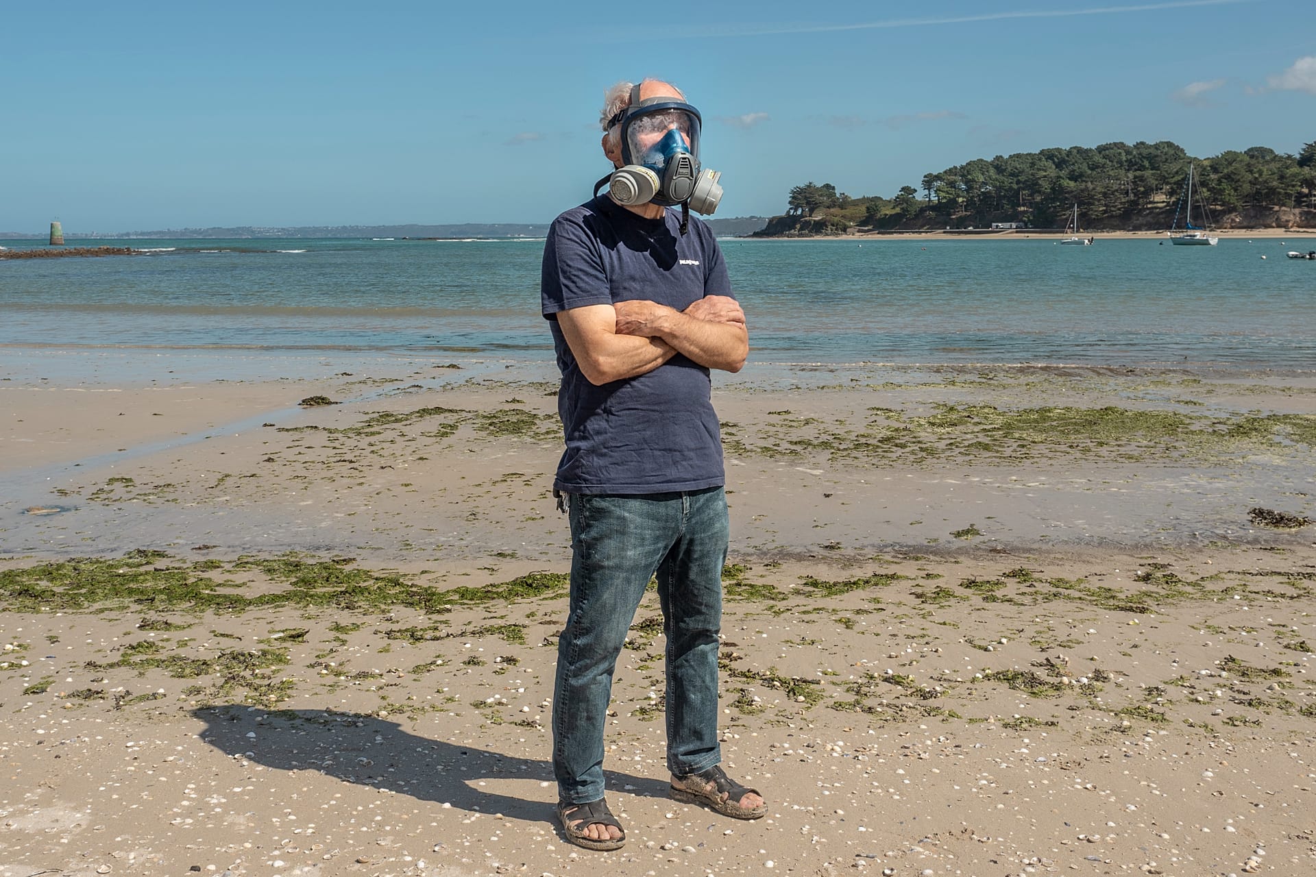 Ekologik faol Yves-Marie Le Lay suv o‘tlari xavfli darajaga yetganda kiyadigan niqobini Plage du Fond de la Baie plyajida, Bretandagi Locquirecda ko‘rsatmoqda.