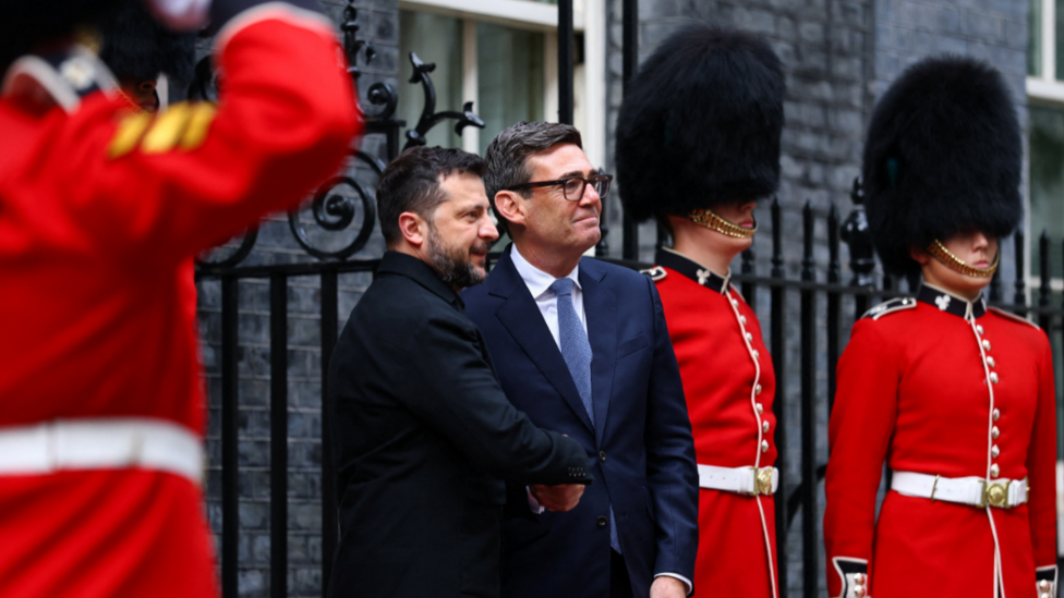 Zelensky and Burnham shake hands next to members of the Irish Guard
