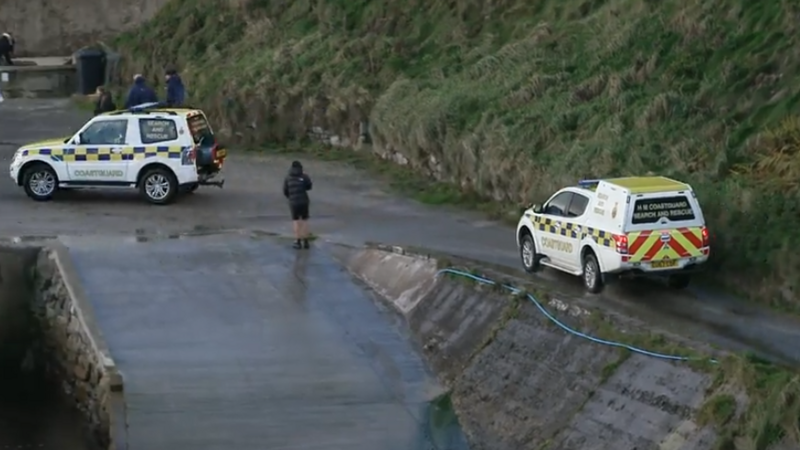 Two coastguard 4x4 vehicles travel along a road at Port of Ness harbour.