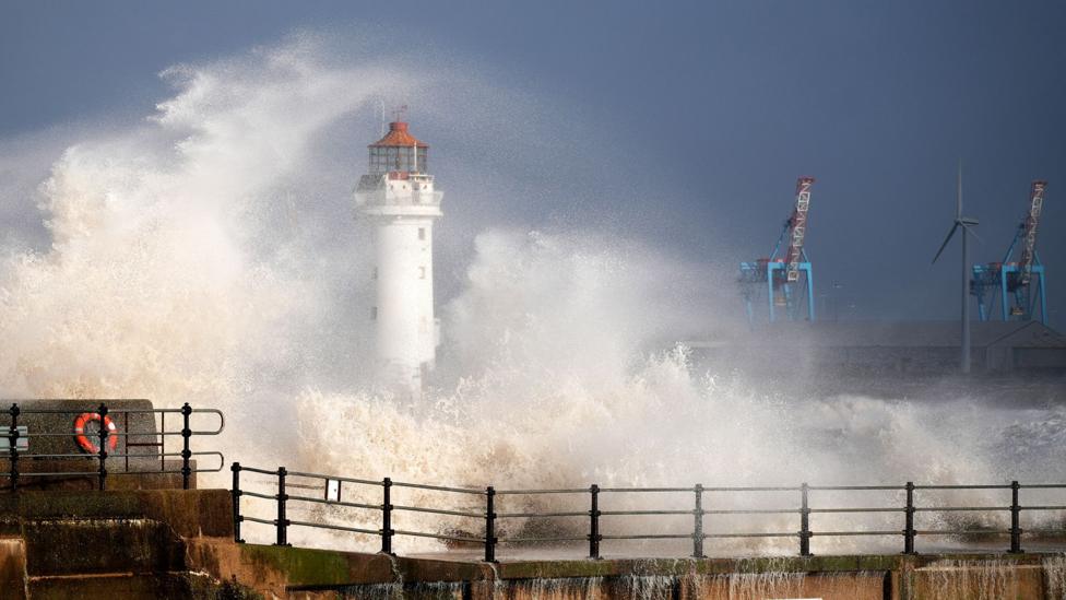 Waves crash over the lighthouse in New Brighton against a dark sky on Sunday.