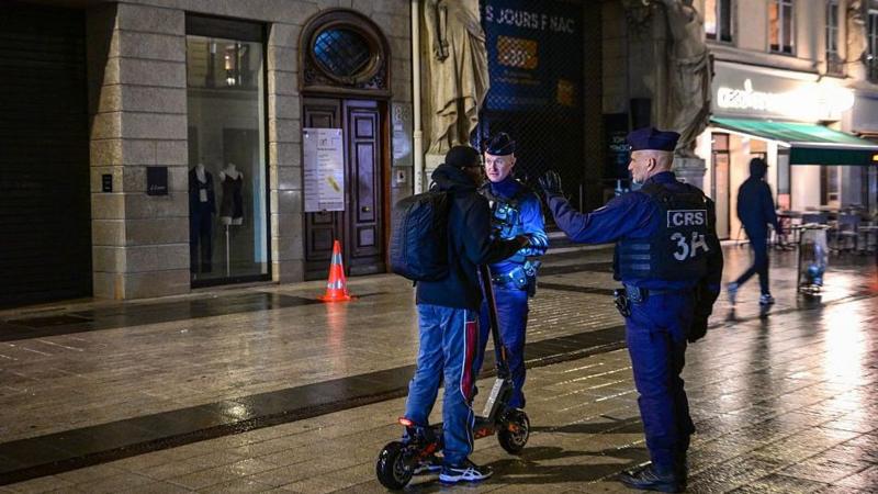 French police officers check a person during a partial curfew in Lyon on October 19